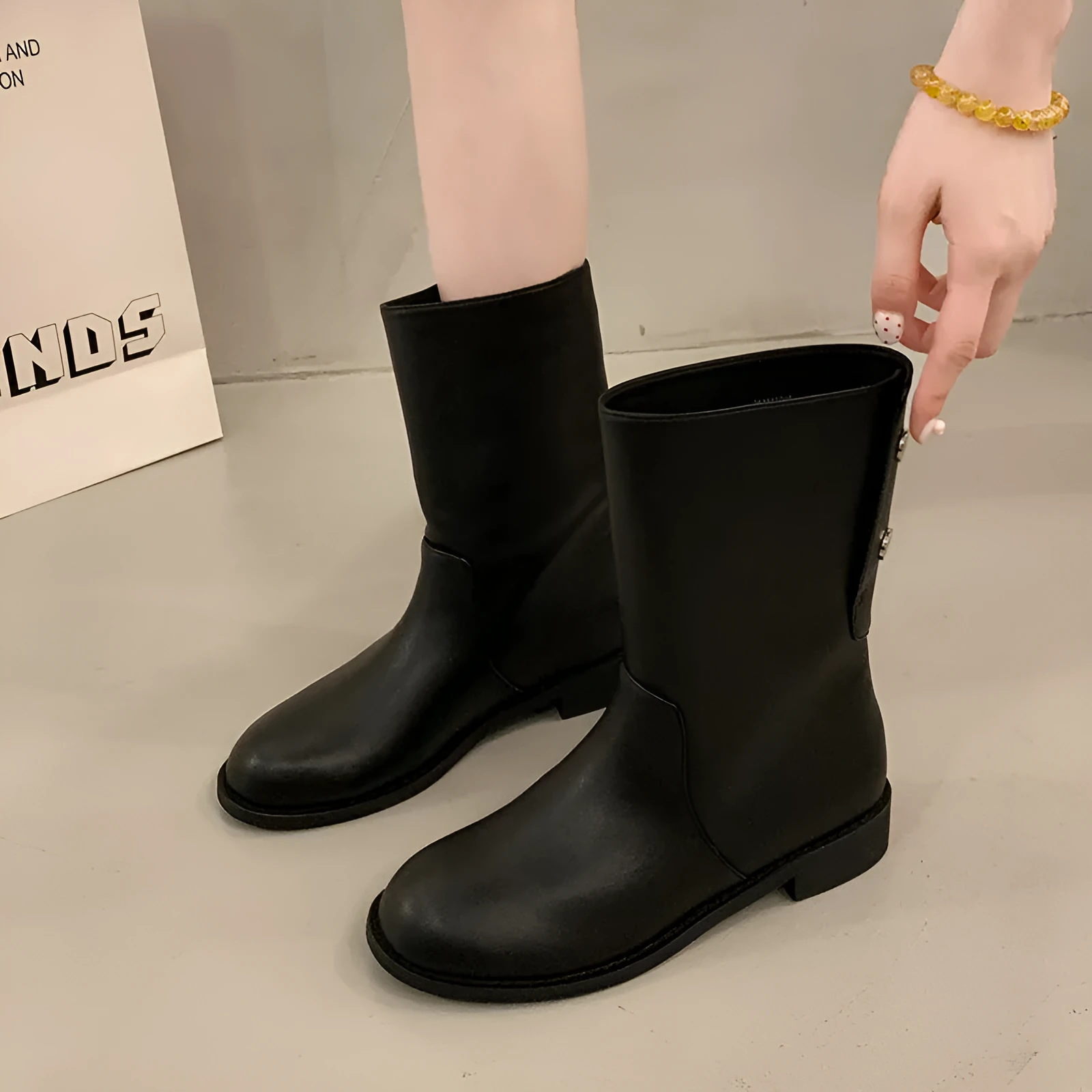 Women's black leather mid-calf platform boots with silver stud details on a white background
