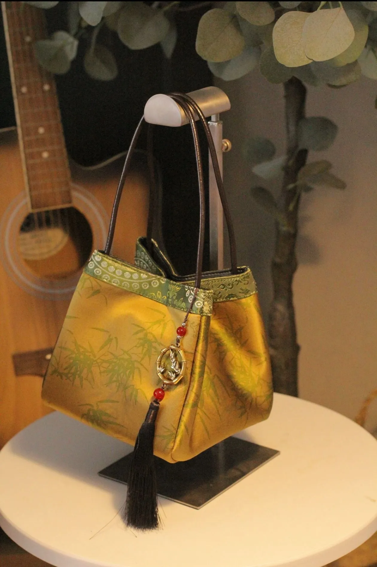 Gold PU leather small square handbag with tassels and sewing line detail on white background