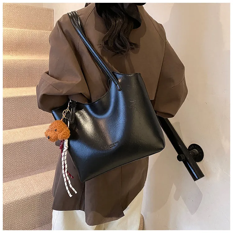 Women's PU commuter shoulder bag in black with stitching details and optional ribbon pendant, horizontal square shape