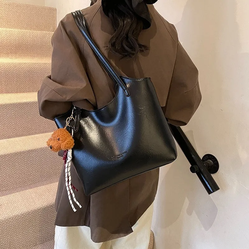 Women's PU commuter shoulder bag in black with stitching details and optional ribbon pendant, horizontal square shape