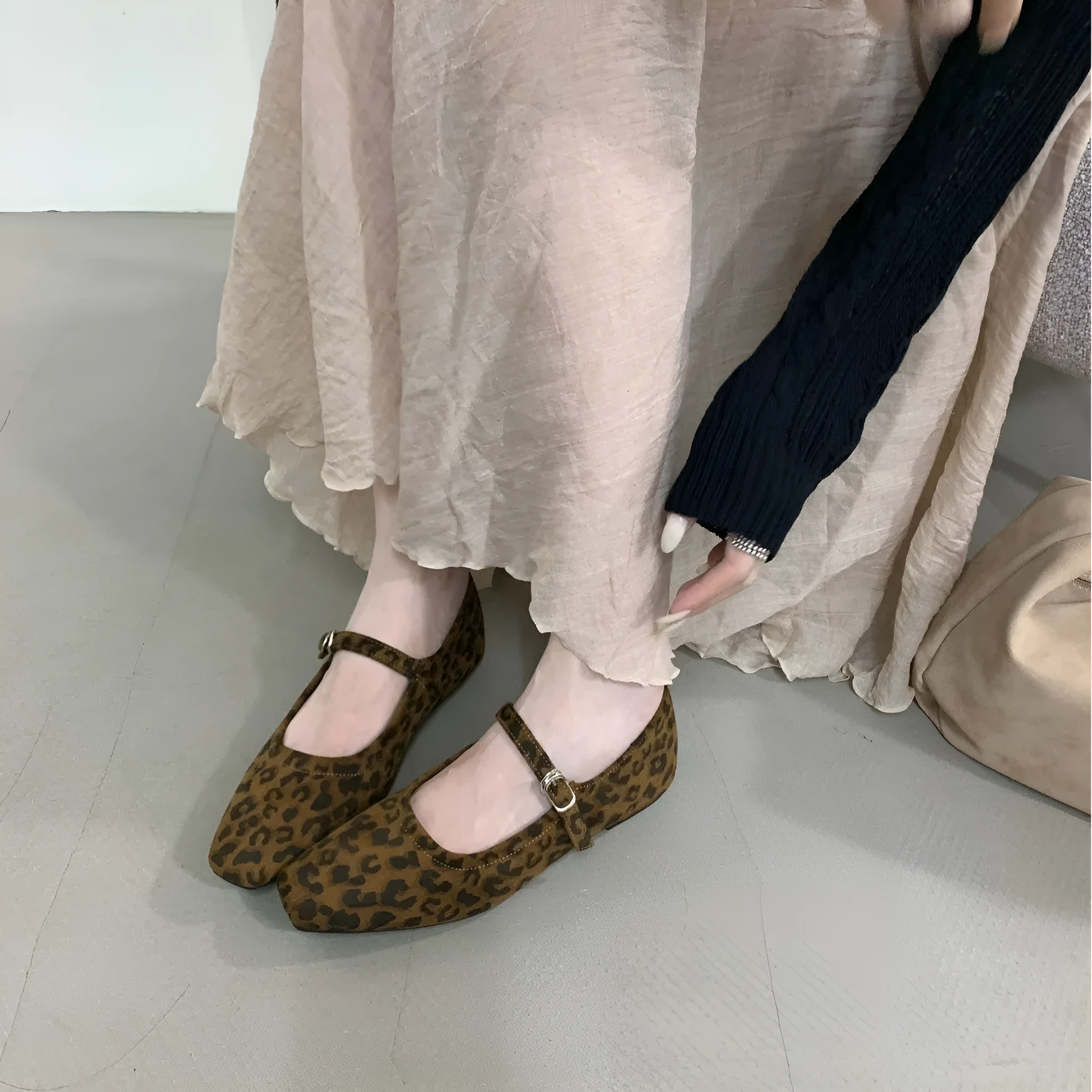 Women's black suede flat shoes with buckle closure and low heel on a neutral background