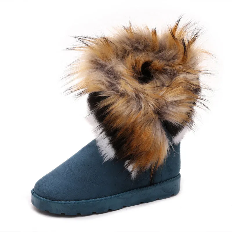 Women's winter snow boots in suede with fluffy fox fur trim and rubber sole on a snowy path