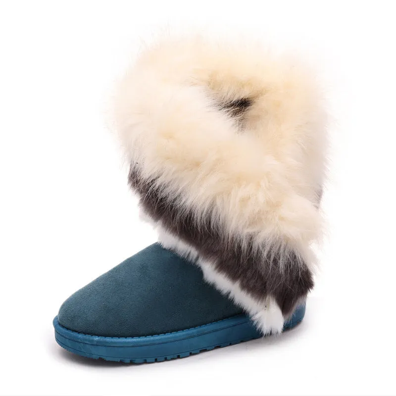 Women's winter snow boots in suede with fluffy fox fur trim and rubber sole on a snowy path