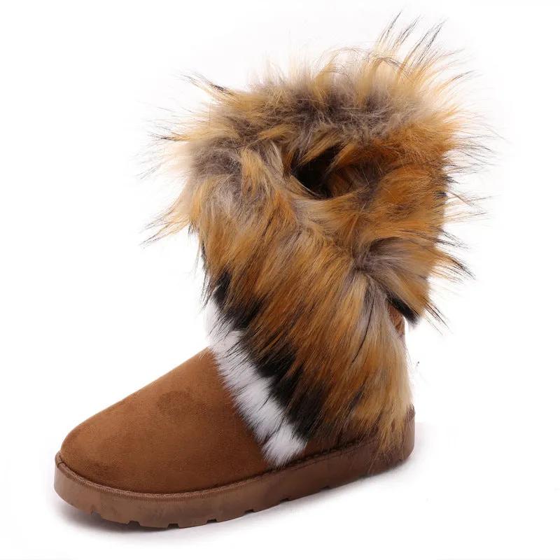 Women's winter snow boots in suede with fluffy fox fur trim and rubber sole on a snowy path