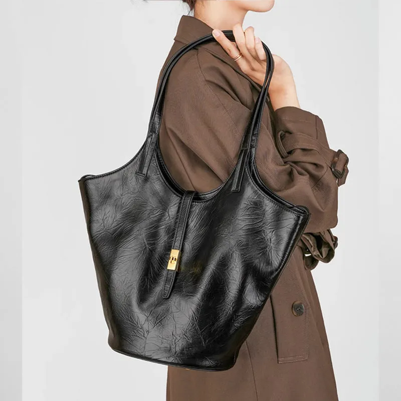 Black genuine leather bucket bag with visible sewing thread detail and crossbody strap on neutral background