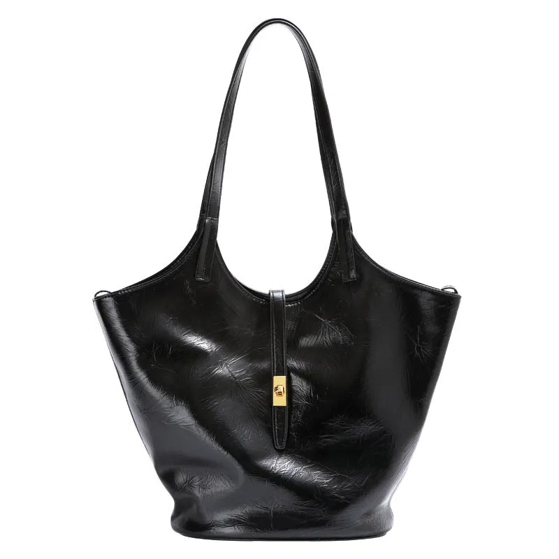 Black genuine leather bucket bag with visible sewing thread detail and crossbody strap on neutral background