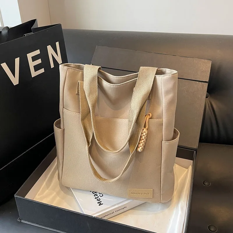 Women's large canvas satchel in beige with shoulder strap, horizontal square shape, and visible sewing thread details