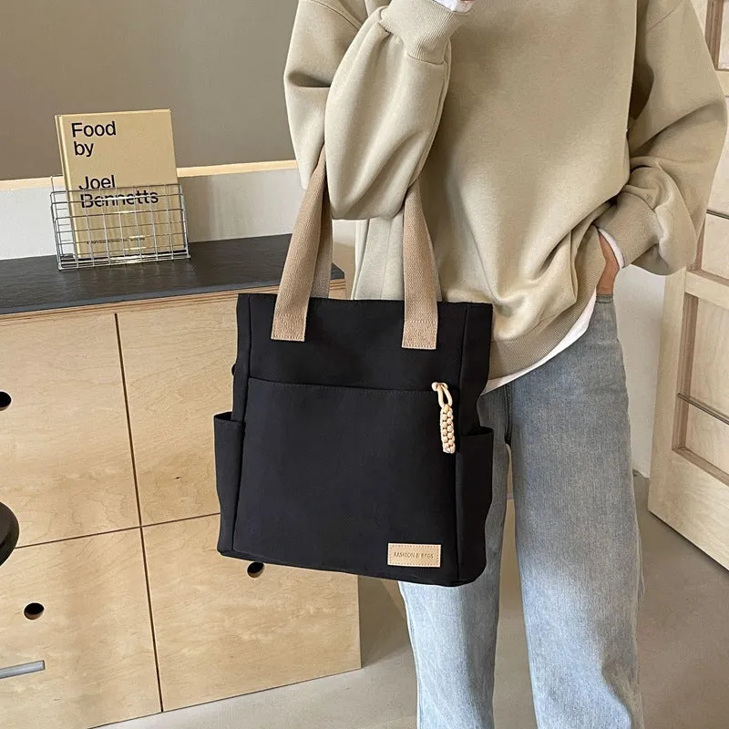 Women's large canvas satchel in beige with shoulder strap, horizontal square shape, and visible sewing thread details