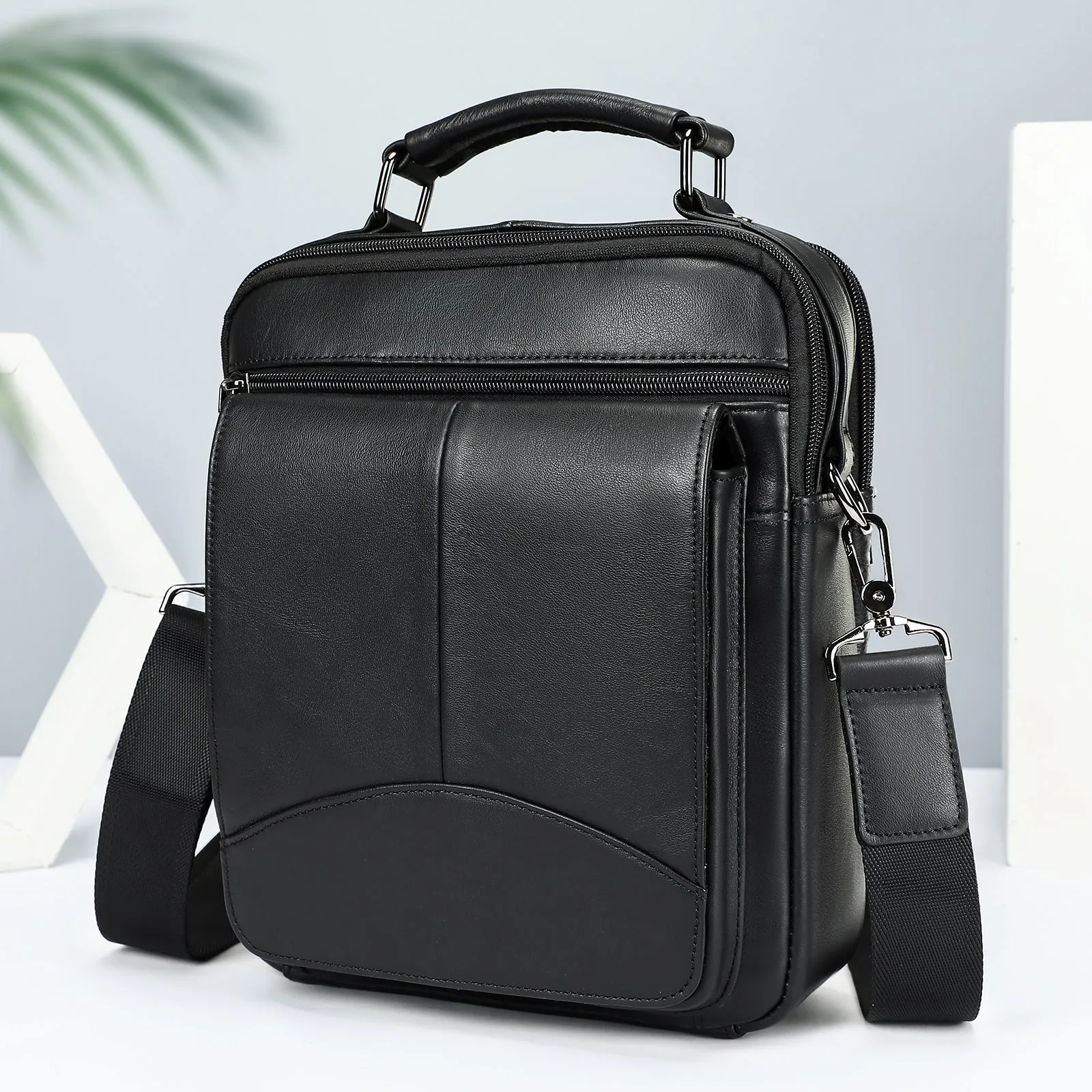 Men's genuine leather messenger bag in black with visible sewing line details and shoulder strap