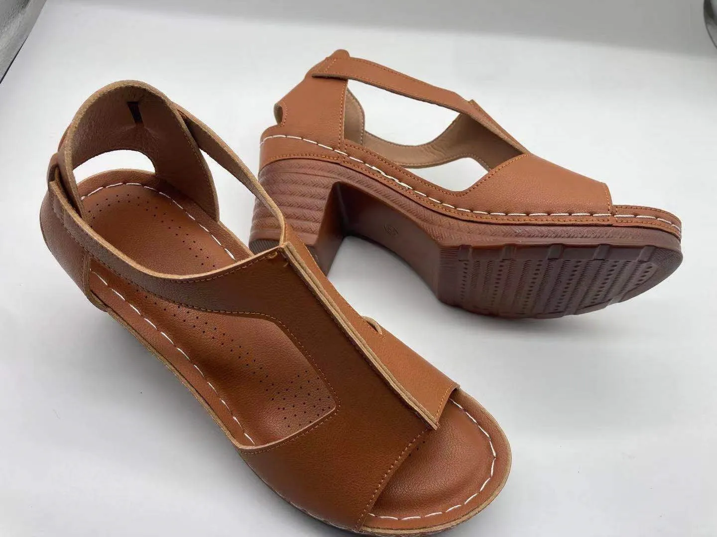 Womens beige Roman style wedge sandals with open peep toe and silver buckle strap on a low heel.
