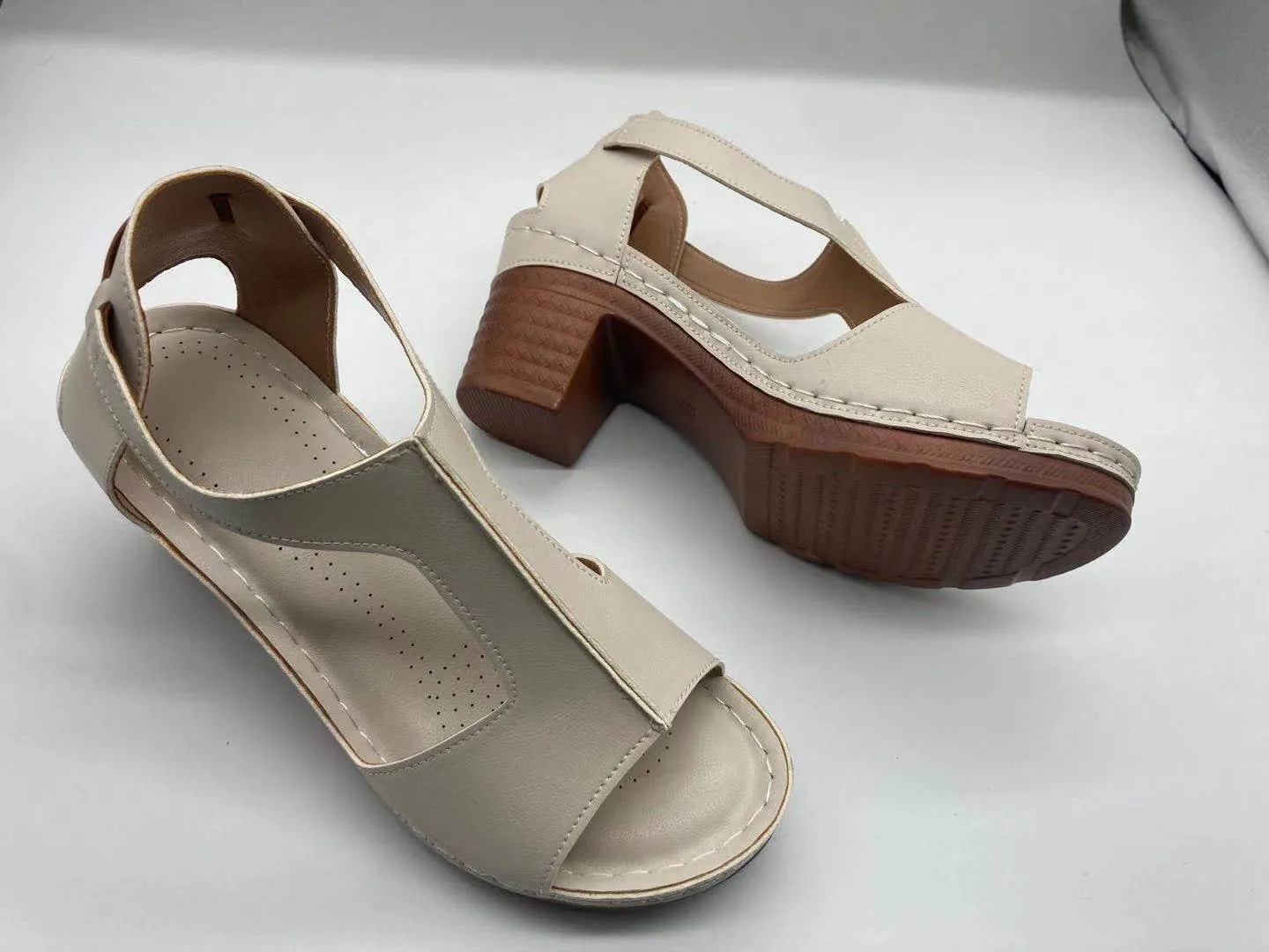Womens beige Roman style wedge sandals with open peep toe and silver buckle strap on a low heel.