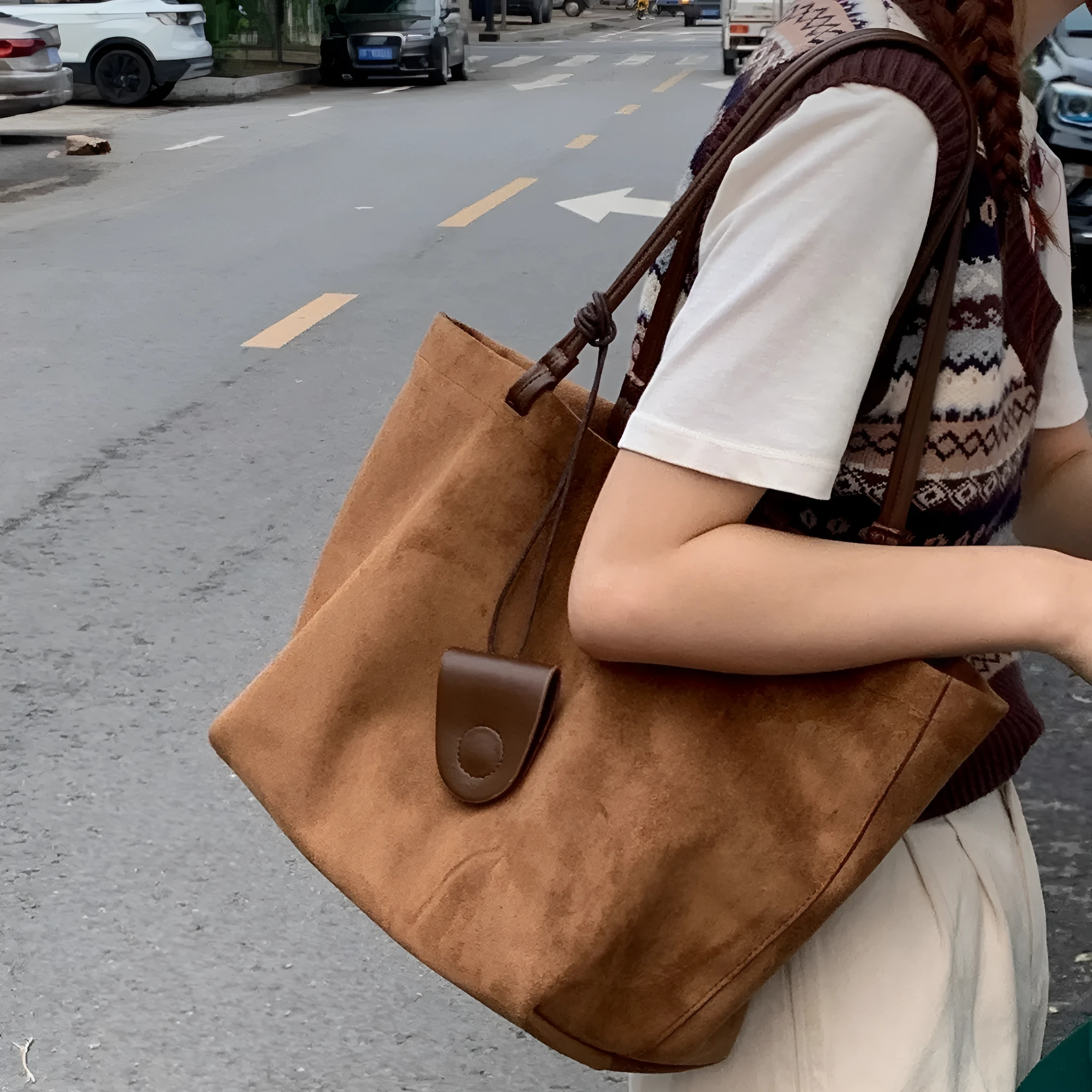 Brown suede shoulder bag with double straps and sewing line detail on a white background