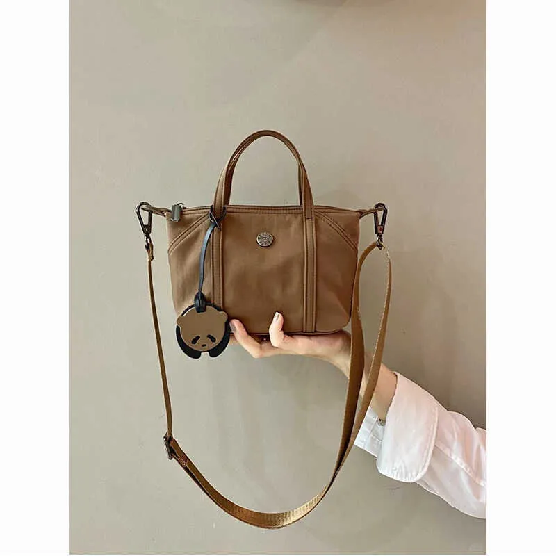 Casual lightweight nylon crossbody bag in dumpling shape, available colours black brown orange pink yellow, with pendant