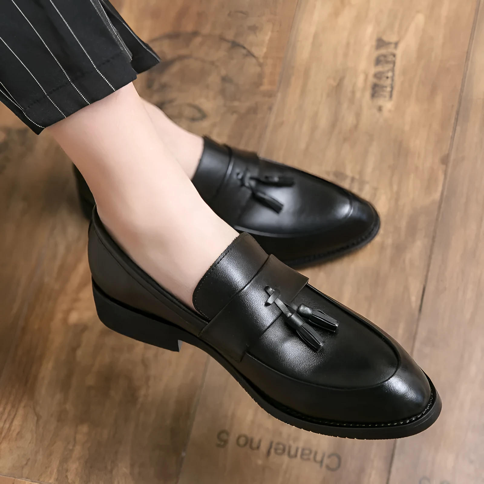 Men's black slip-on business casual shoe with tassel detail and rubber sole.
