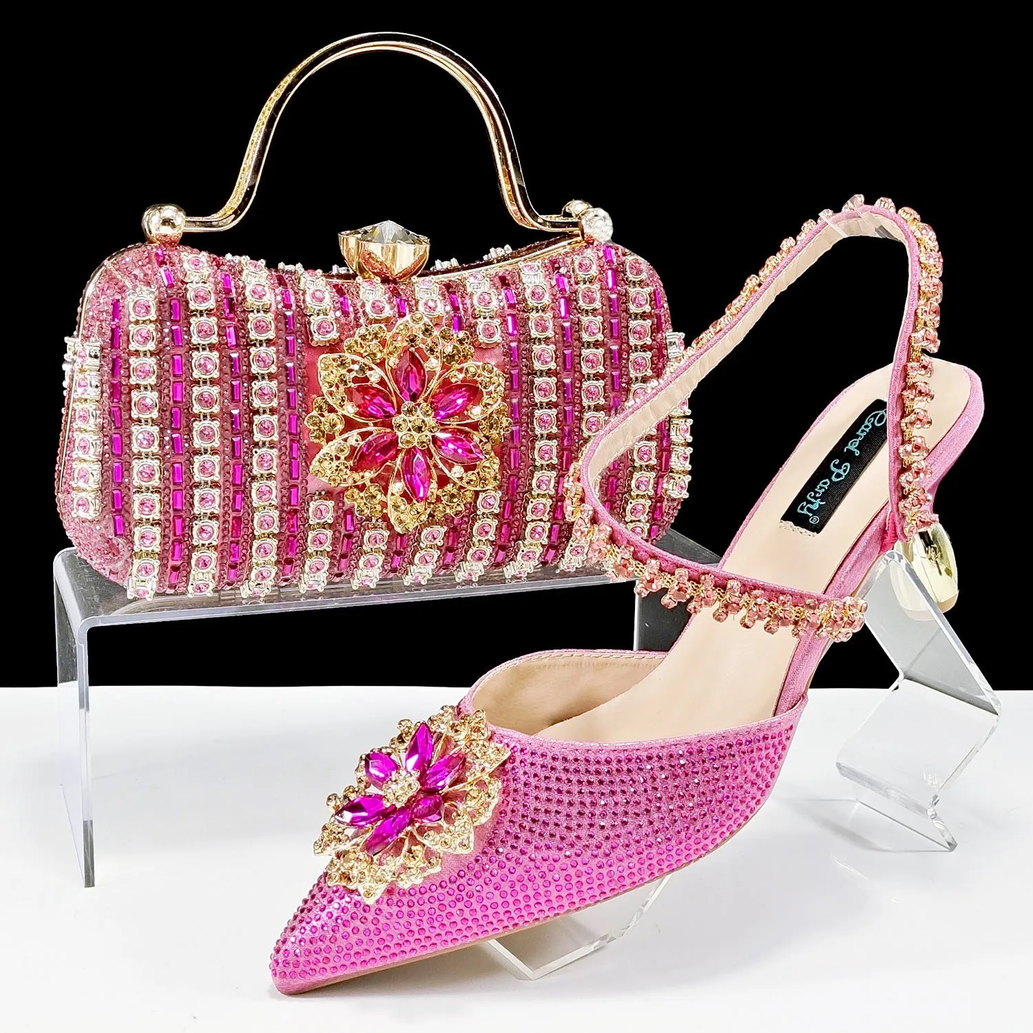 Women's black high-heel ankle strap sandal with rhinestone flower buckle and matching hard clutch bag.