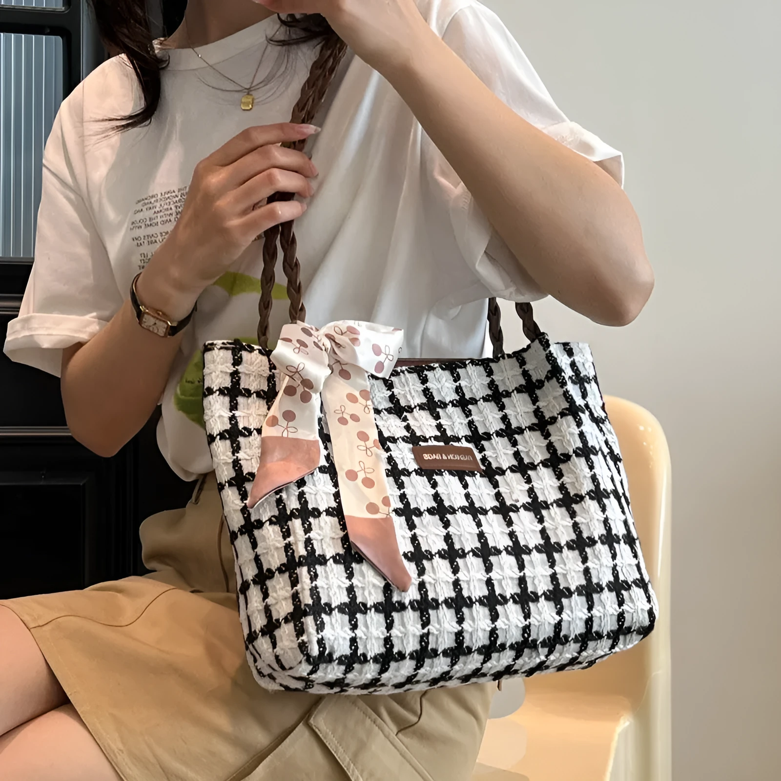 Black woven wool shoulder bag with horizontal square shape showing internal organiser compartments