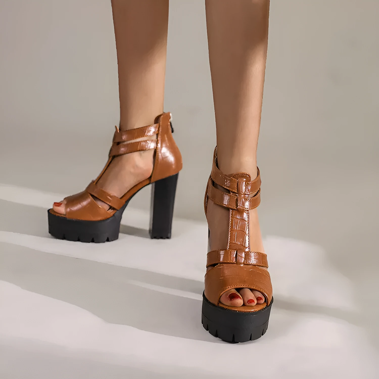 A pair of black platform high heel sandals with a back zipper and round toe on a rubber sole.