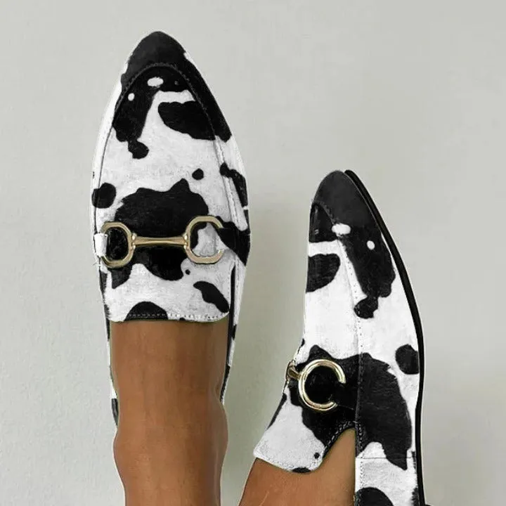 Women's black and white cow pattern pointed-toe mules with flat square heel on a neutral background