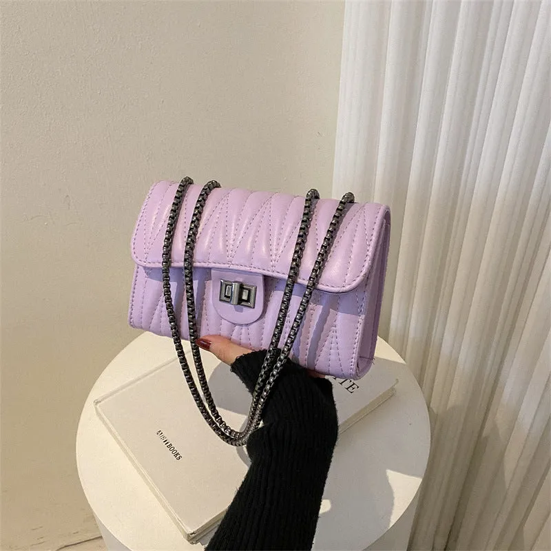 Small beige textured diamond pattern PU women's handbag with a soft handle on a table.