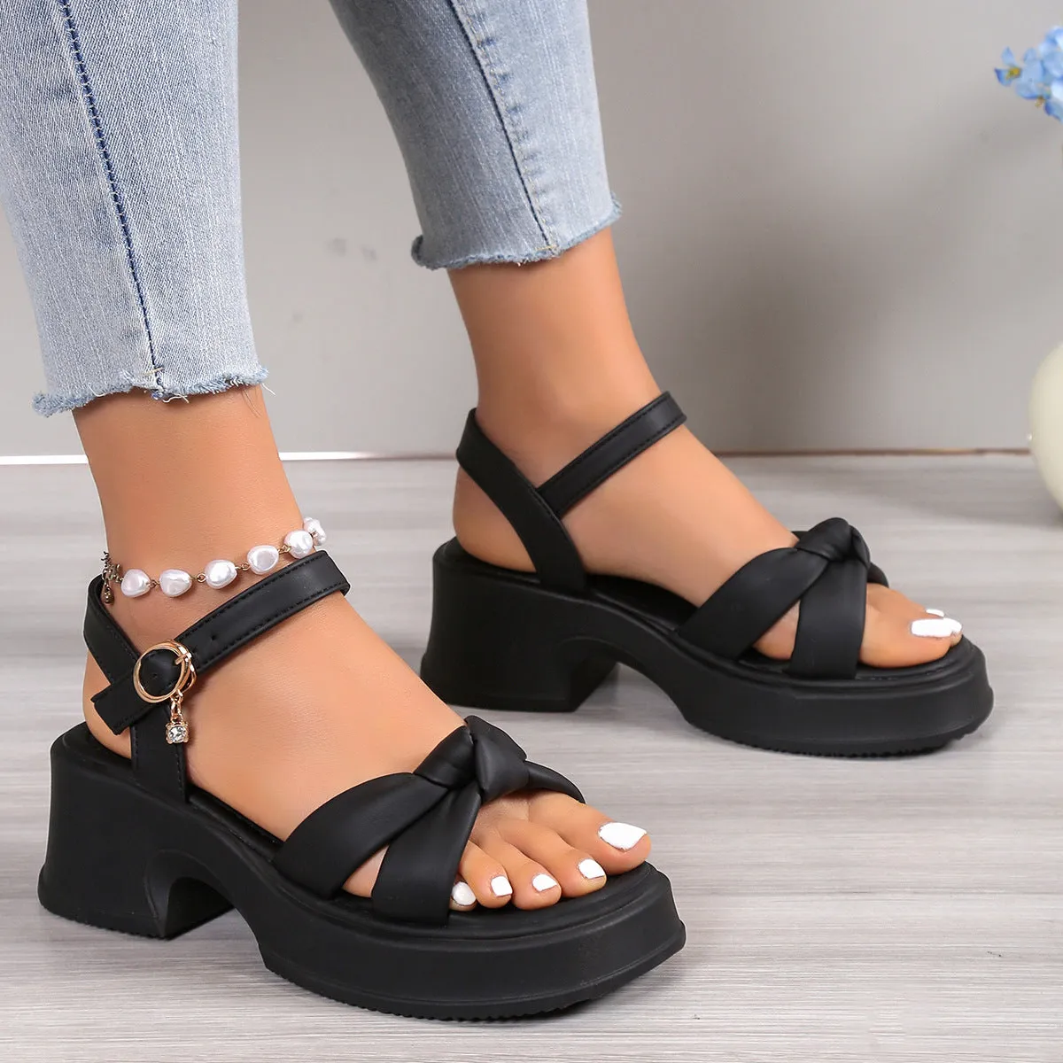 Black high-heel slippers with a thick rubber sole and a button fastening over the instep.
