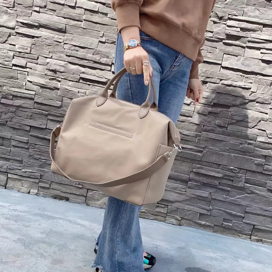 Black nylon waterproof shoulder bag with leather trim, showing large main compartment and shoulder strap.