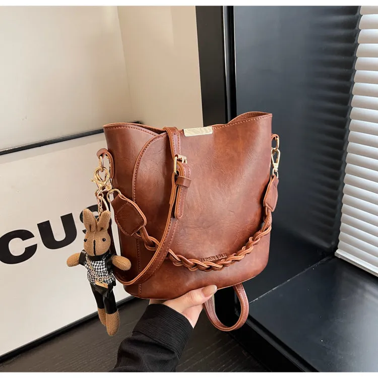 Women's retro PU messenger bag in brown with compact bucket shape, pendant, and double shoulder strap connector