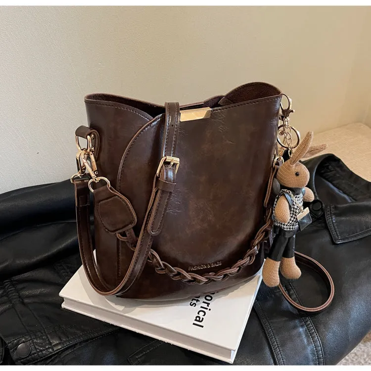 Women's retro PU messenger bag in brown with compact bucket shape, pendant, and double shoulder strap connector