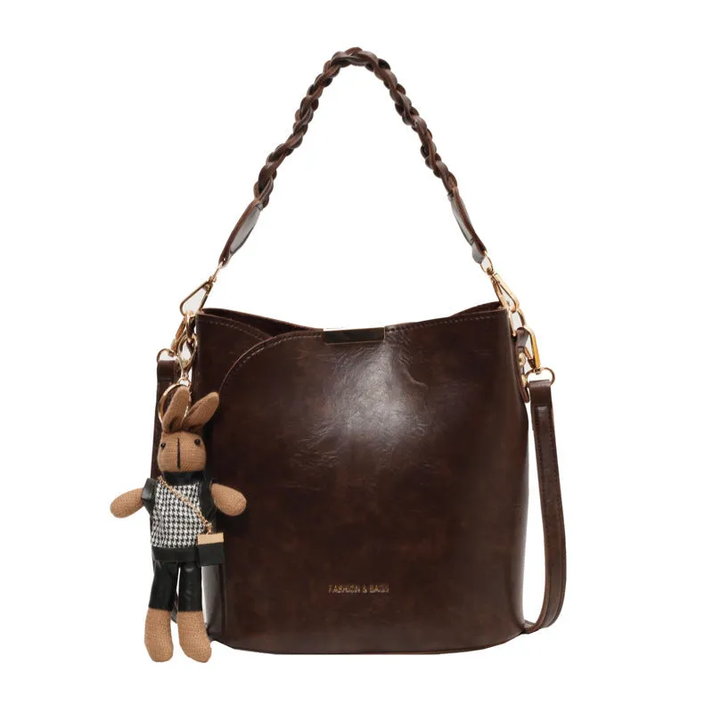 Women's retro PU messenger bag in brown with compact bucket shape, pendant, and double shoulder strap connector