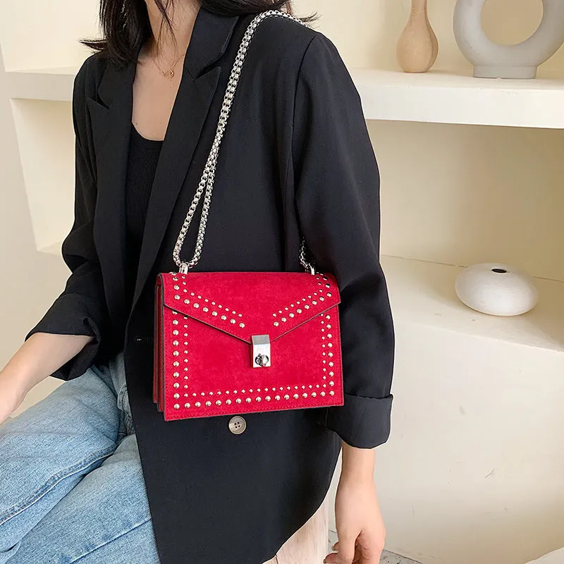 Small PU shoulder messenger bag for women with lock detail, chains, and rivet decoration on a soft flap.