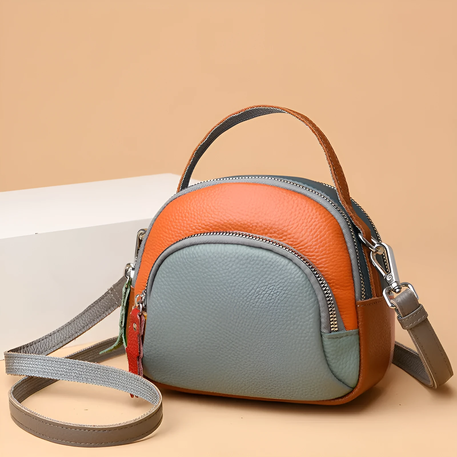 Round hand-held crossbody bag made from first layer cowhide leather with visible sewing line detail on exterior
