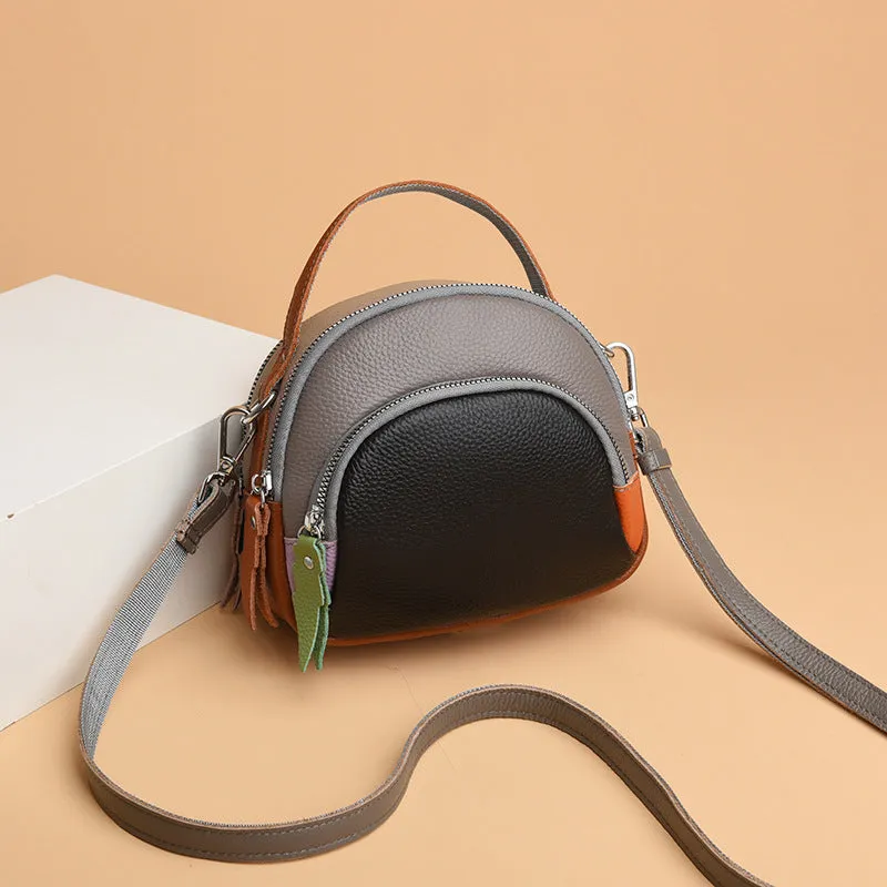 Round hand-held crossbody bag made from first layer cowhide leather with visible sewing line detail on exterior