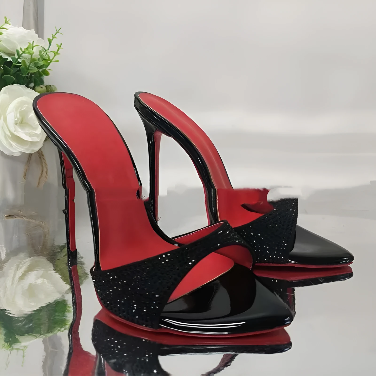 Black rhinestone ankle-strap open toe sandal with super high heel and pointed toe on white background