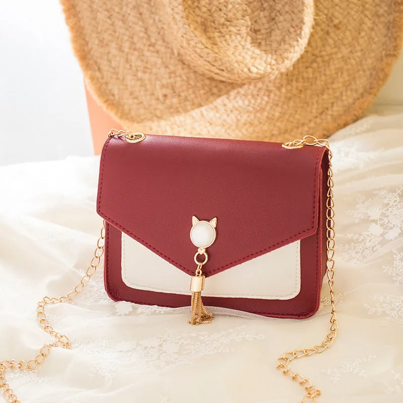 Small square PU leather crossbody bag with cat tassel decoration, magnetic flap, and adjustable chain strap in black