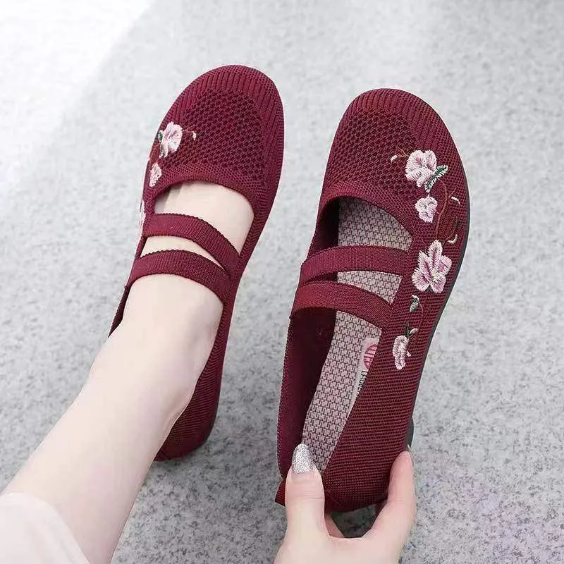 A pair of casual slip-on flat shoes with a round toe and elastic fabric upper, shown in an embroidered colour option.