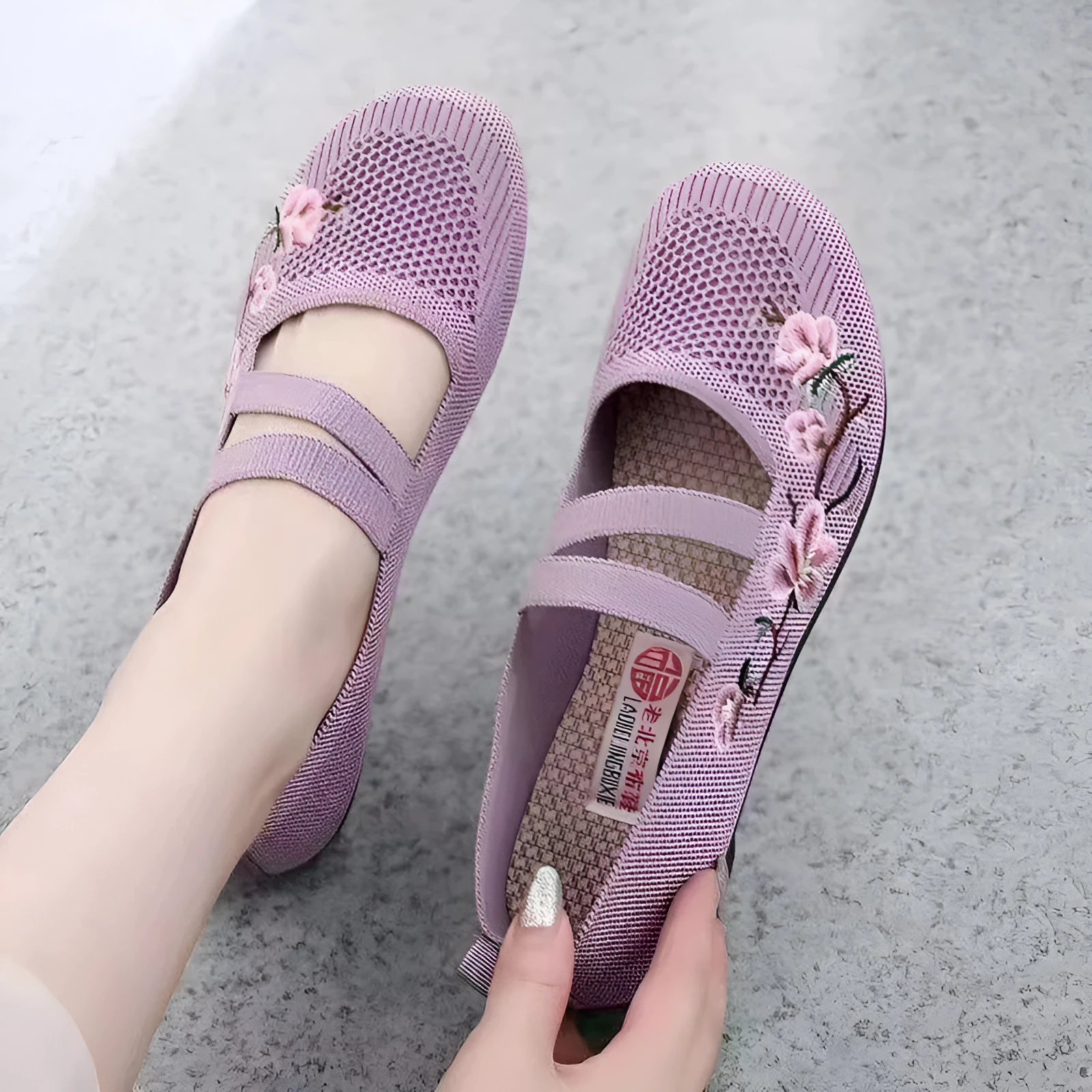 A pair of casual slip-on flat shoes with a round toe and elastic fabric upper, shown in an embroidered colour option.