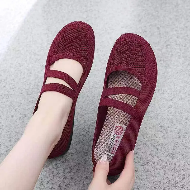 A pair of casual slip-on flat shoes with a round toe and elastic fabric upper, shown in an embroidered colour option.