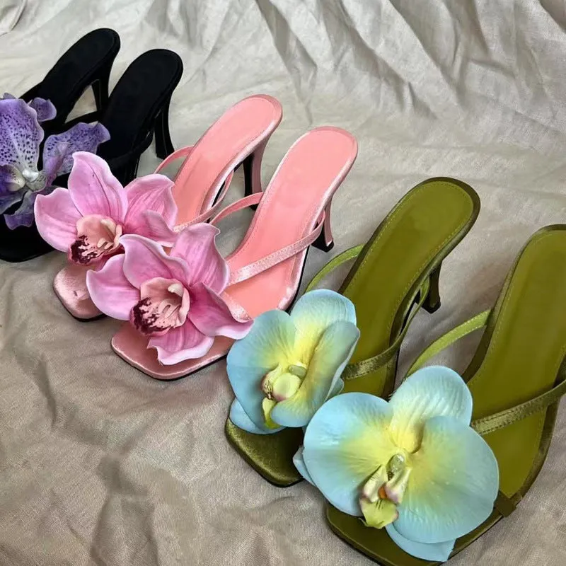 Pink women's sandals with a satin upper, artificial white Phalaenopsis flower, square toe, and a mid heel.