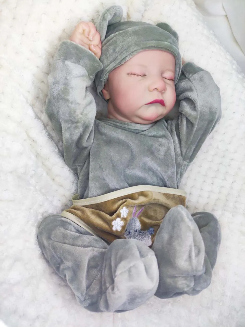 18-inch reborn doll with cloth body in soft pink romper sitting on table
