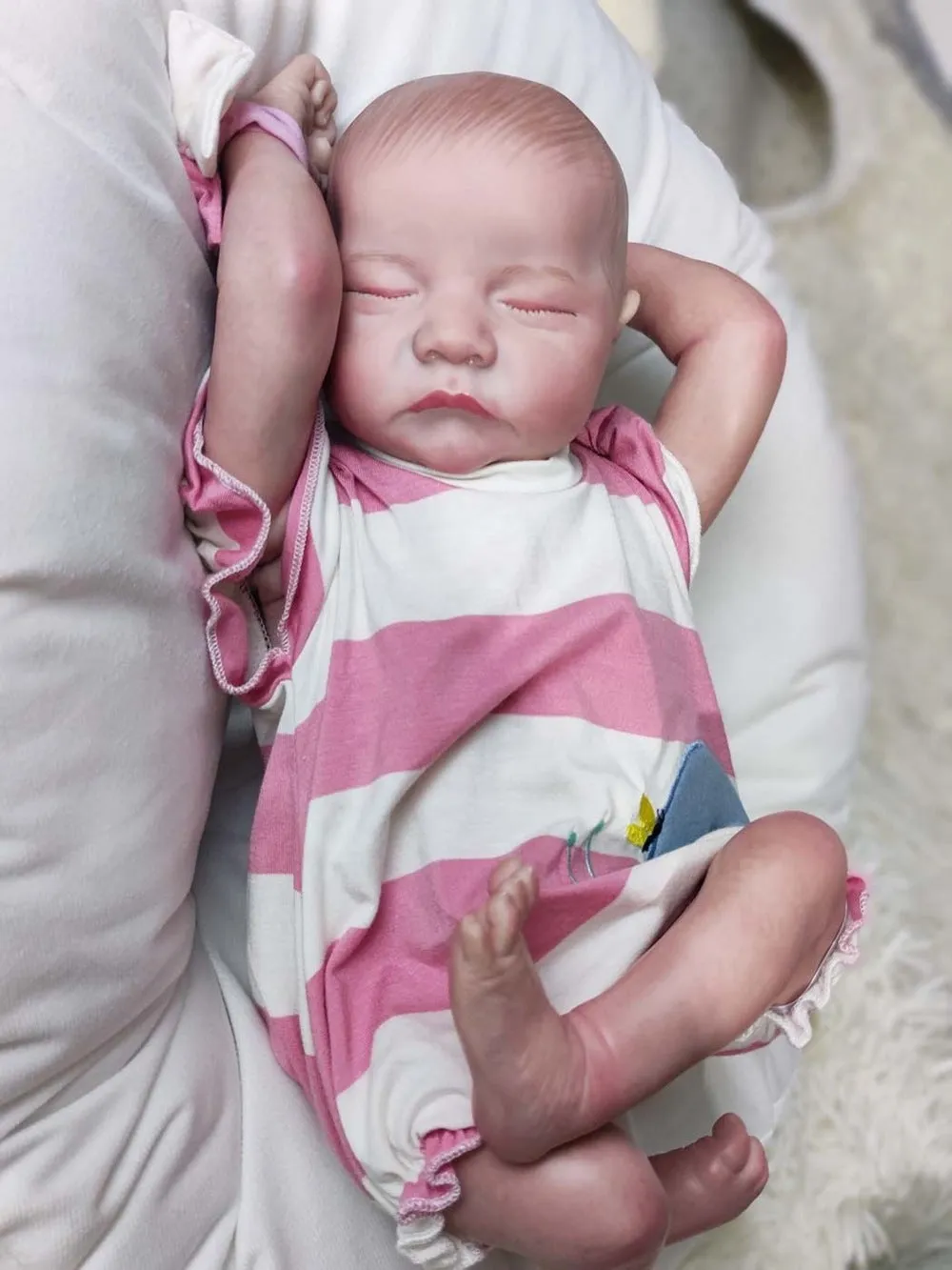 18-inch reborn doll with cloth body in soft pink romper sitting on table