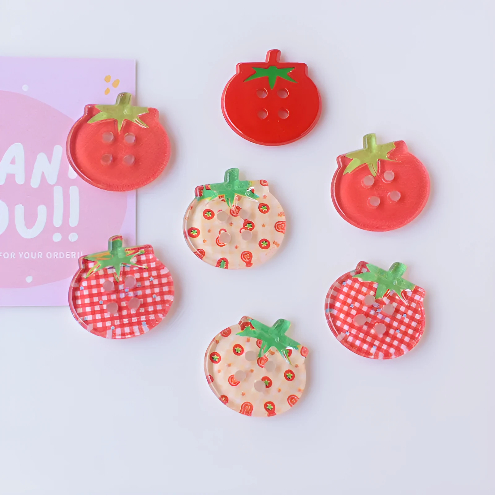A pack of medium-sized plastic tomato button ornaments in mixed colours including red plaid and cherry tomato print.