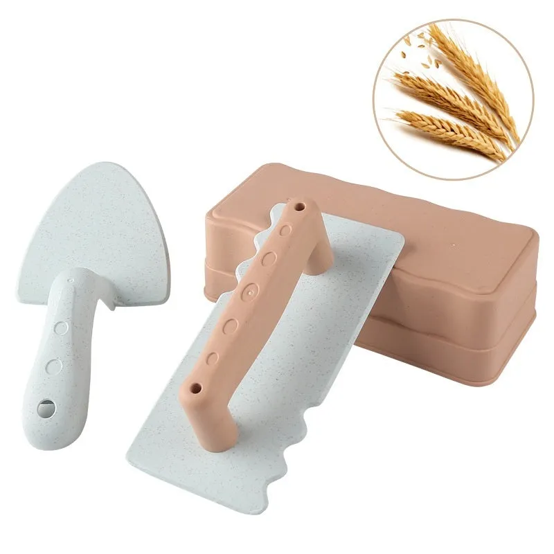 Wheat straw sand shovel brick toy in brown, 19 cm long, on sand with blurred background