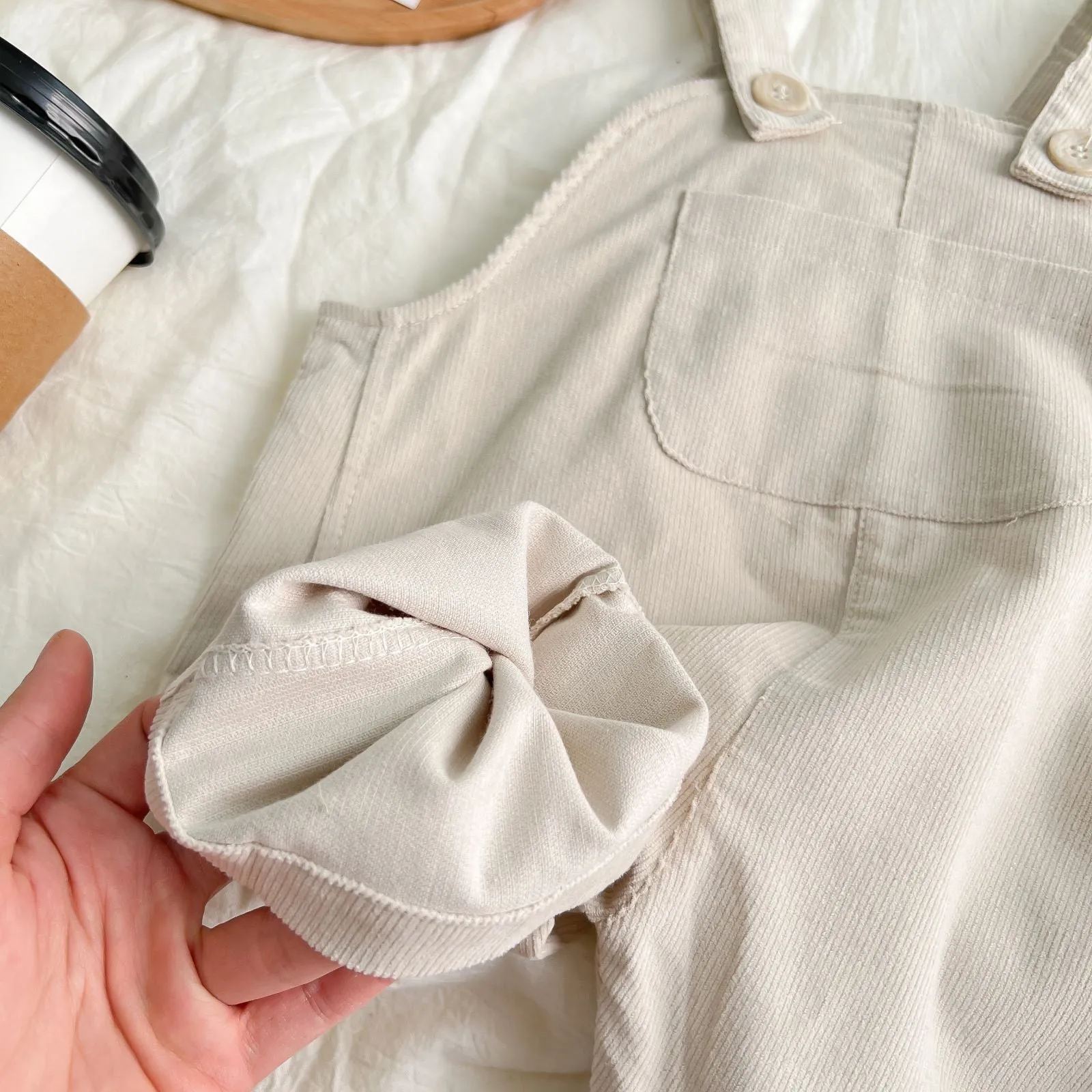 Infant cotton corduroy overalls in creamy white with large front pockets and double-breasted closure