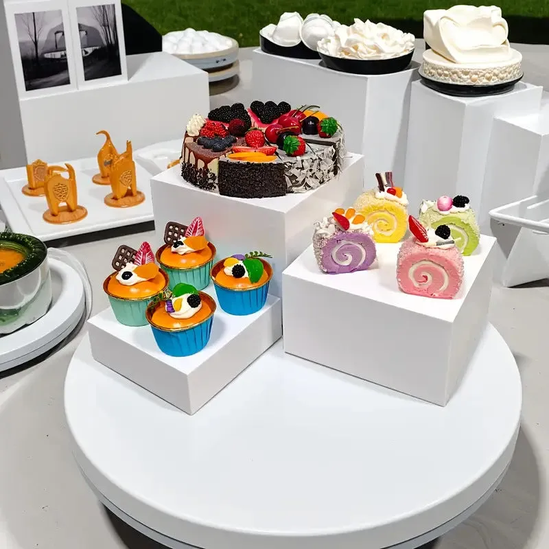 Set of six white plastic tiered dessert display stands arranged on a table.