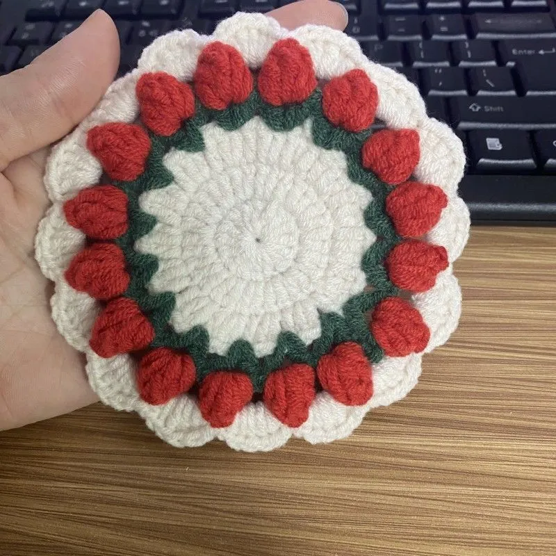 Handmade woven floral coaster in cotton and linen yarn on a wooden table