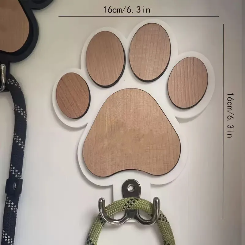 Black wooden wall hook with raised paw print design against a white wall.