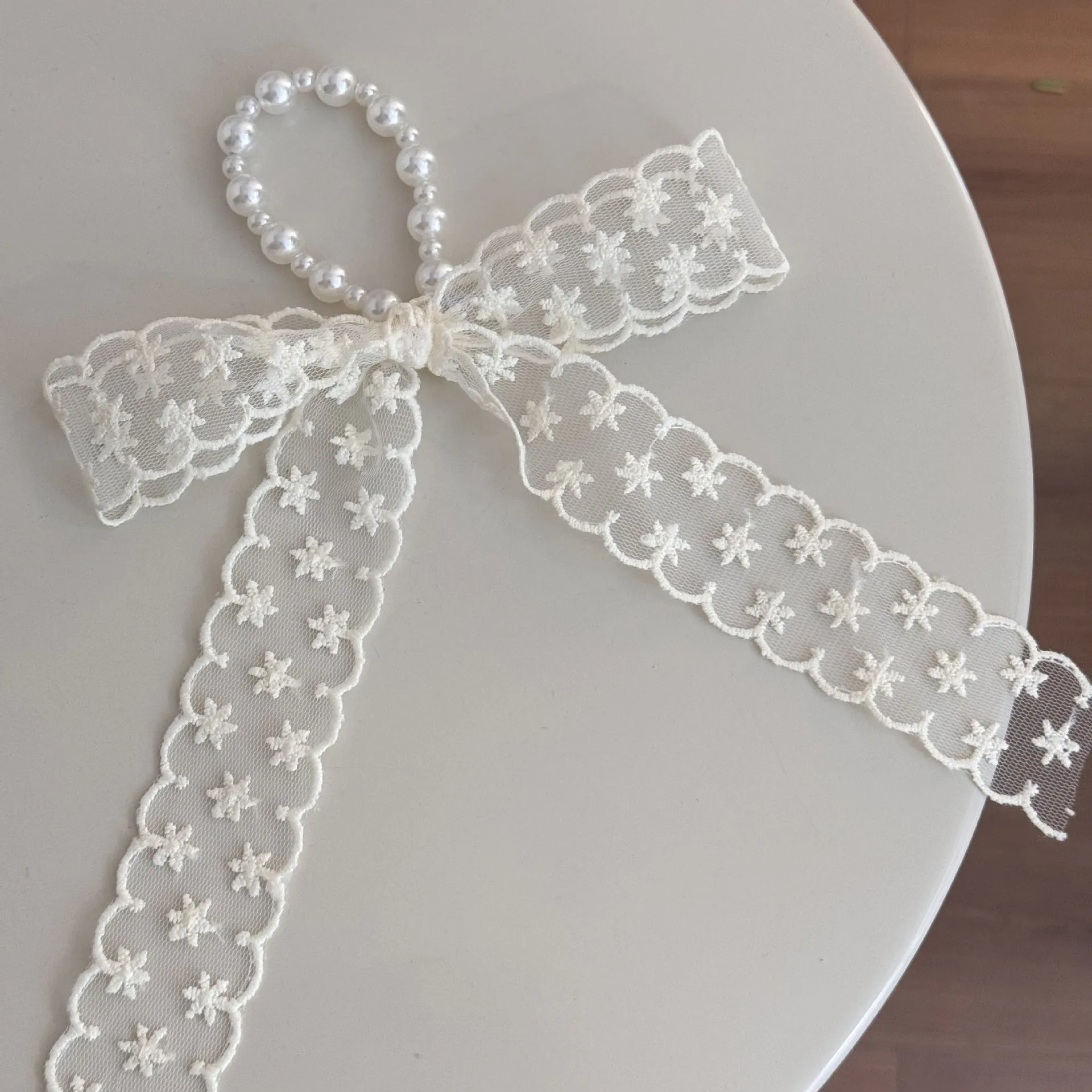 A women's hair clip barrette with a soft blue cloth bow and lace decoration on a plastic clip.