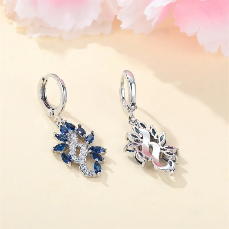 A pair of platinum sapphire blue alloy drop dangle earrings for women on a plain background.