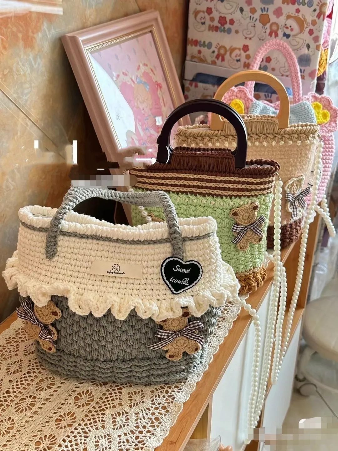 Wool crocheted bear shoulder bag with wooden handle and adjustable strap in one of four decorative styles