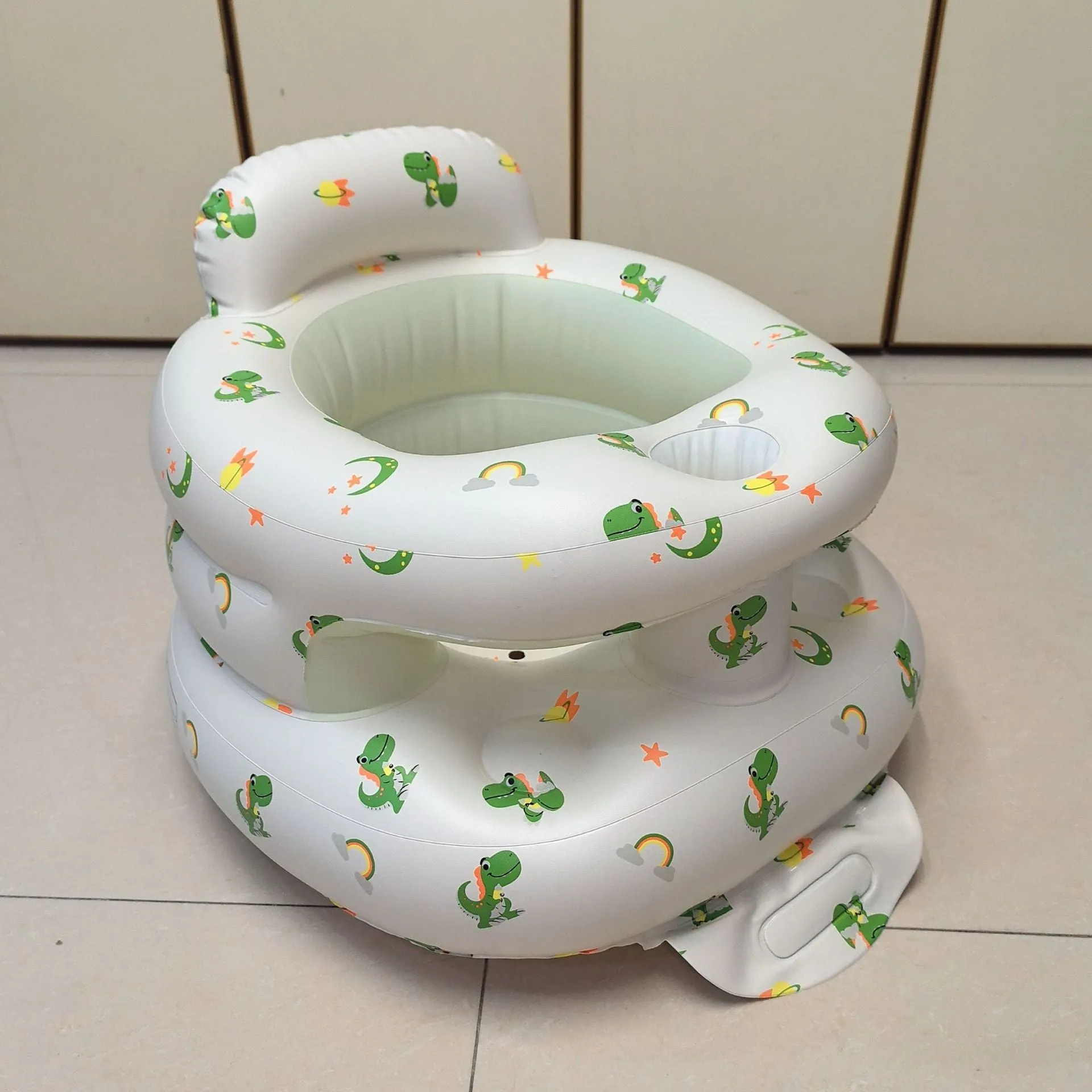Inflatable infant dining chair in PVC with bear design, deflated beside a baby for scale