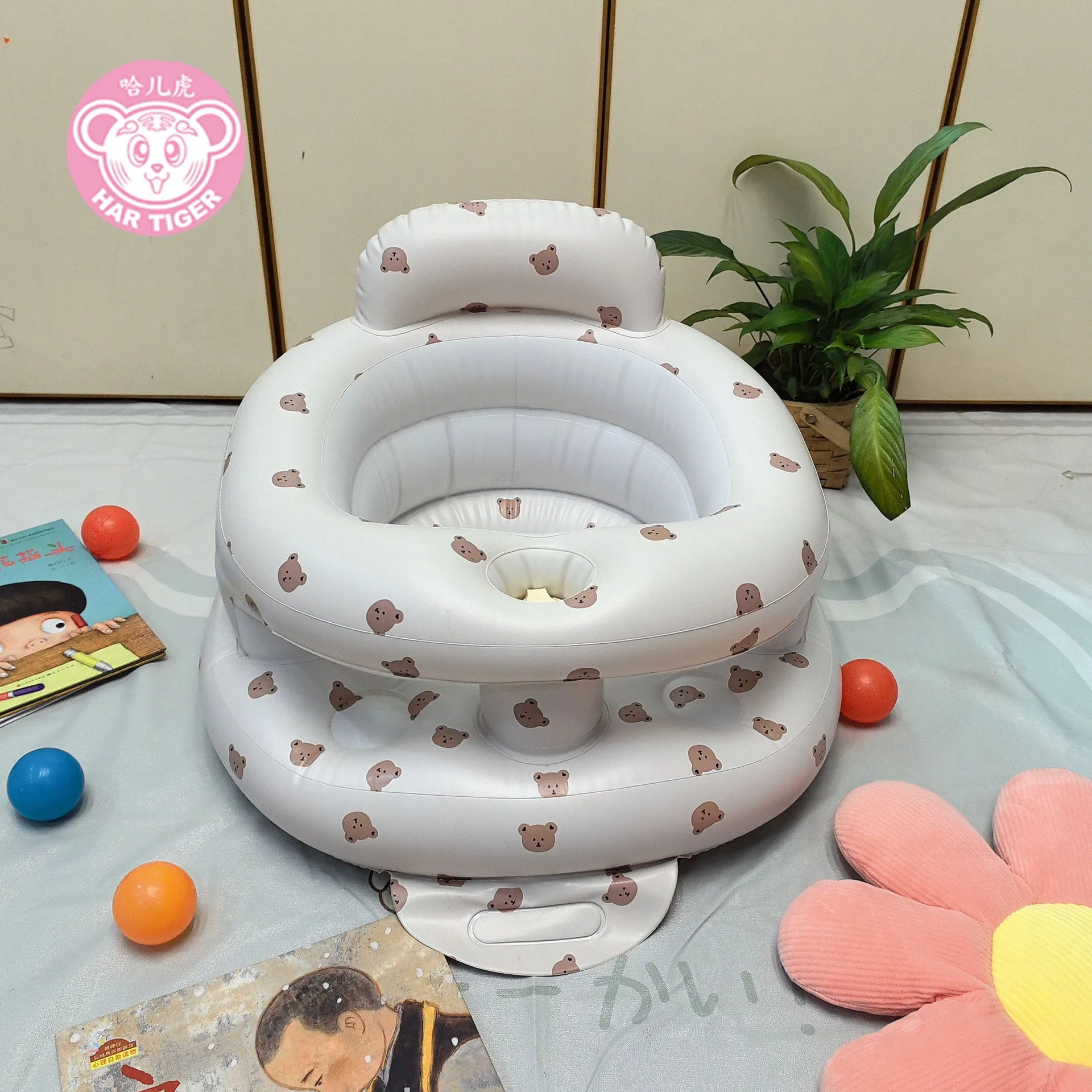Inflatable infant dining chair in PVC with bear design, deflated beside a baby for scale
